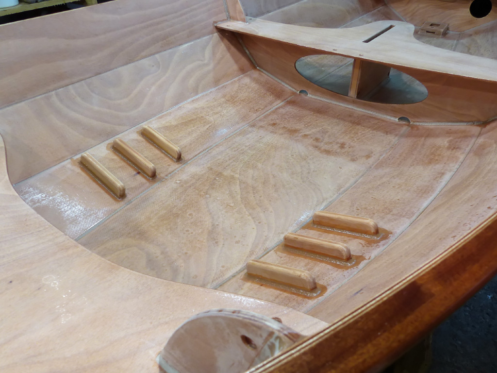 J'ai ensuite viss&eacute;-coll&eacute; les trois paires de cale-pieds. Il est indispensable de pouvoir se caler les pieds pour ramer efficacement. En effet, la nage &agrave; l'aviron est une question de leviers et d'appuis : la pale de l'aviron prend appui sur l'eau, la dame de nage est le pivot, et &agrave; l'autre bout du levier constitu&eacute; par l'aviron la main tire sur la poign&eacute;e. L'effort transmis &agrave; l'aviron d&eacute;pend de l'appui disponible au pied du nageur : la main ne tire efficacement que si le corps est cal&eacute;. L'effort de propulsion est transmis au bateau par les dames de nage.