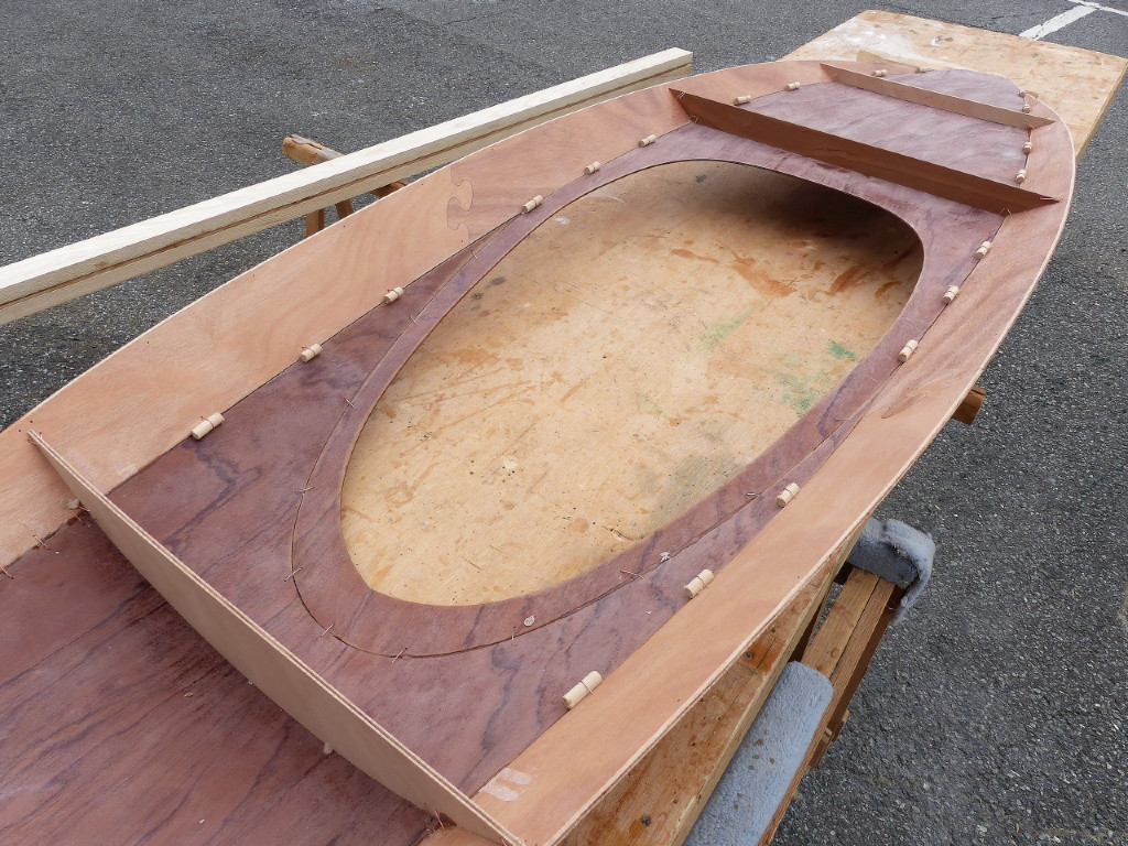 Je retourne le pont du Wood Duckling apr&egrave;s que l'&eacute;poxy du premier collage ait durci. Notez les petits segments de tourillon de 12mm que j'ai ajout&eacute; dans les sutures afin d'am&eacute;liorer l'alignement des panneaux. Je m'appr&ecirc;te &agrave; couper les sutures en fil de cuivre pour les extraire et d&eacute;poser les couples temporaires. 