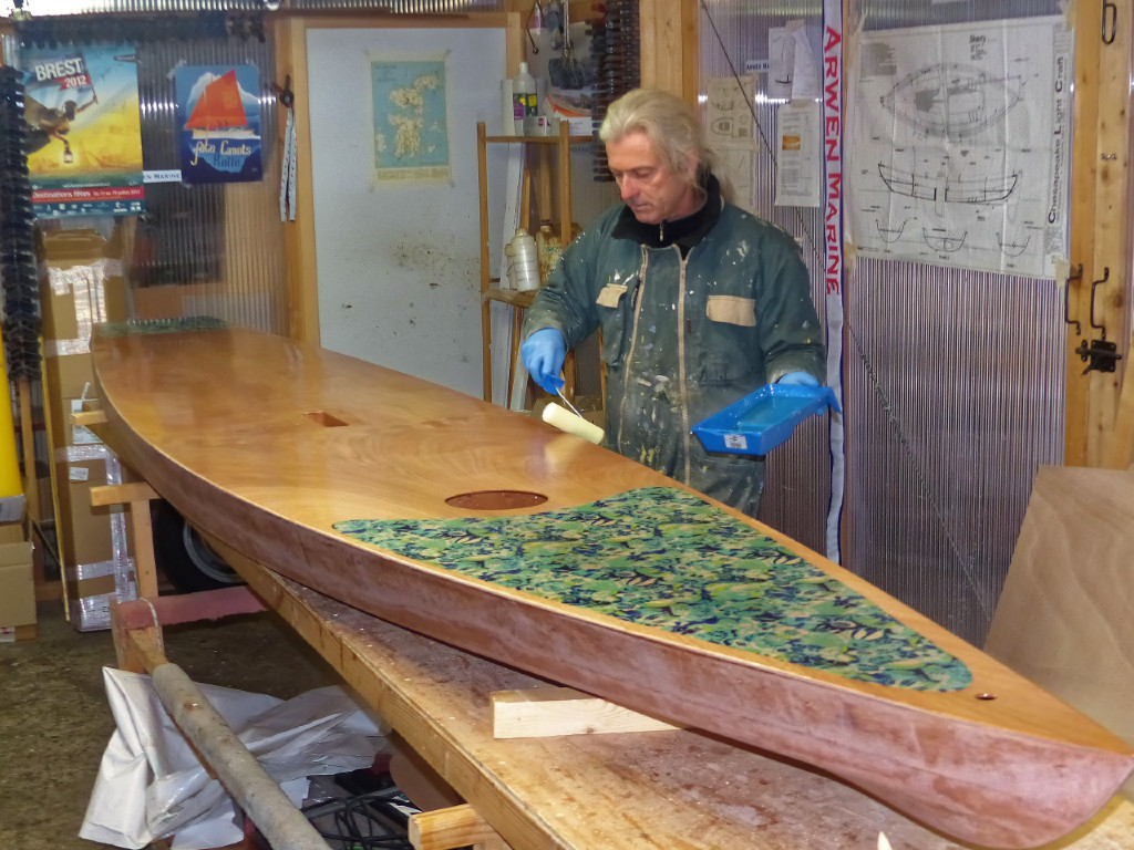 Frédéric passe une dernière couche d'époxy sur l'ensemble de la surface de la Kaholo après que nous ayons posé des bandes de fibre de verre sur les arêtes de la poignée de portage afin de les renforcer et repassé une couche sur les joints-congés de la boite du vide-poches afin d'assurer son étanchéité intérieure. 