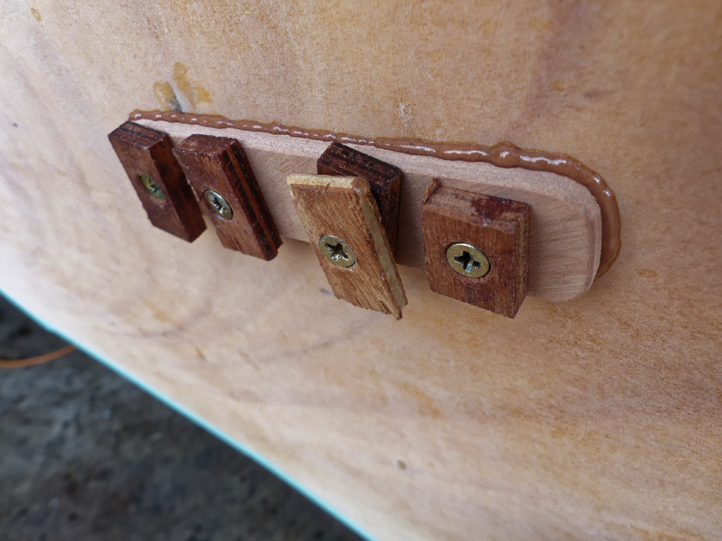 Je colle aussi une plaque sur le tableau à l'endroit du femelot du haut, car celui du bas est en saillie et la géométrie de la charnière n'était pas optimale. Les vis qui pressent le collage sont dans les trous des vis de montage du fémelot. 