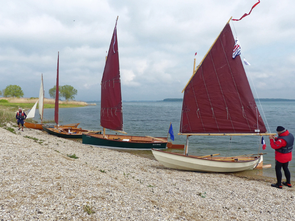 La plage se couvre peu à peu de bateaux prêts à prendre la mer (j'ai essayé, mais "prendre le lac" parait bizarre...) De gauche à droite, le Doryplume "Prise de Ris'k" de Bernard, le Skerry Raid "Truk" d'Yves, mon Goat Island Skiff (en raccourci GIS) "Let's Goat!", et le Skerry "L'Odet" de Jean-François. 