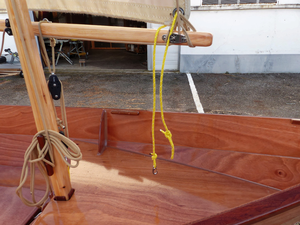 Après avoir hissé la voile, nous allons nouer le "bêleur", (le petit cordage jaune) qui a deux fonctions : il plaque la bôme contre le mât et évite que celle-ci se le balance d'avant en arrière.
