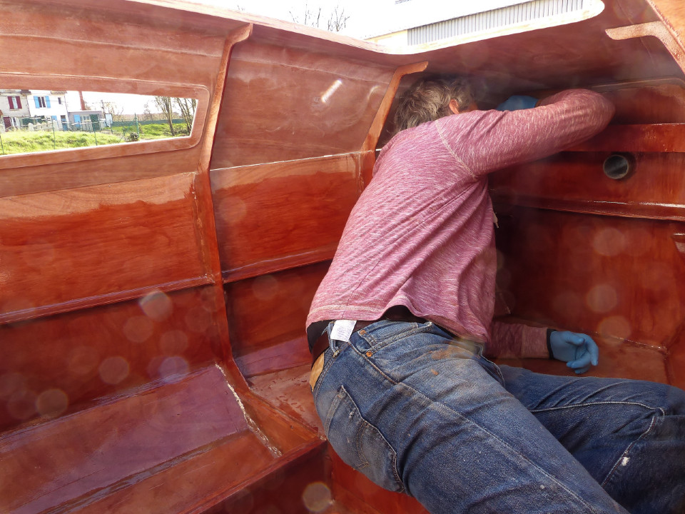 William continue sa couche d'époxy pigmentée à l'intérieur de la cabine. Notez la sortie du tube de bout-dehors qu'il faudra pouvoir obturer. 