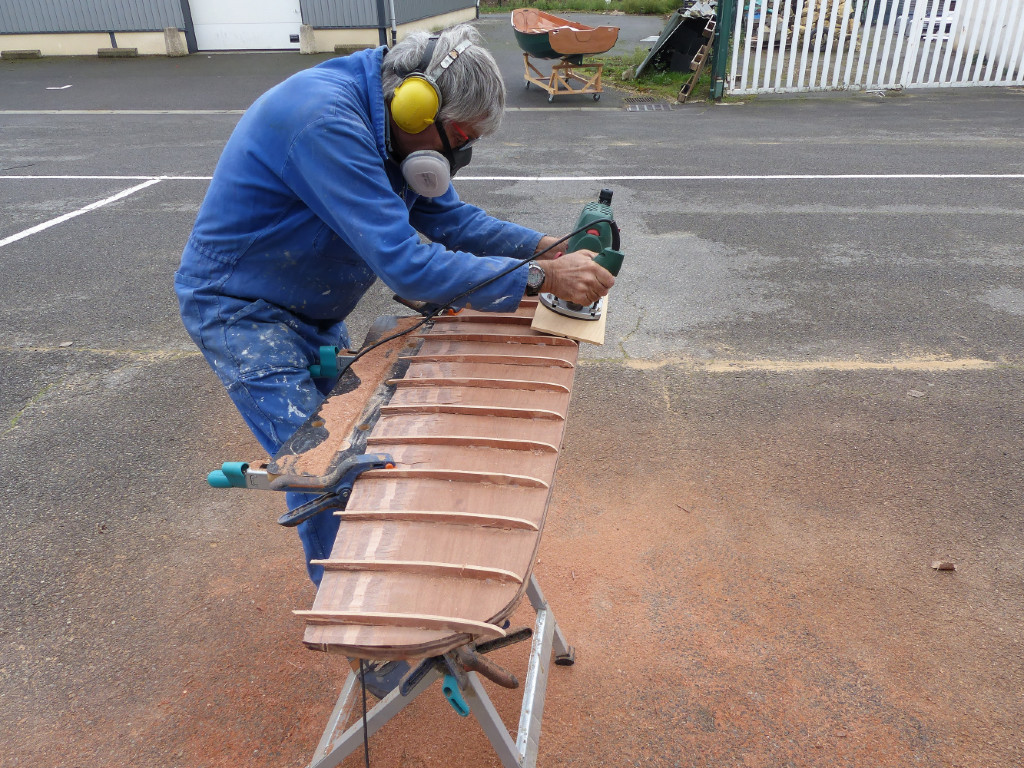 Après durcissement des collages, nous profilons le safran et la dérive. Le profilage est fait à la défonceuse, qui est guidée grâce à des "nervures" temporaires collées à la colle thermofusible. Ici, Pierre s'occupe de la dérive. 