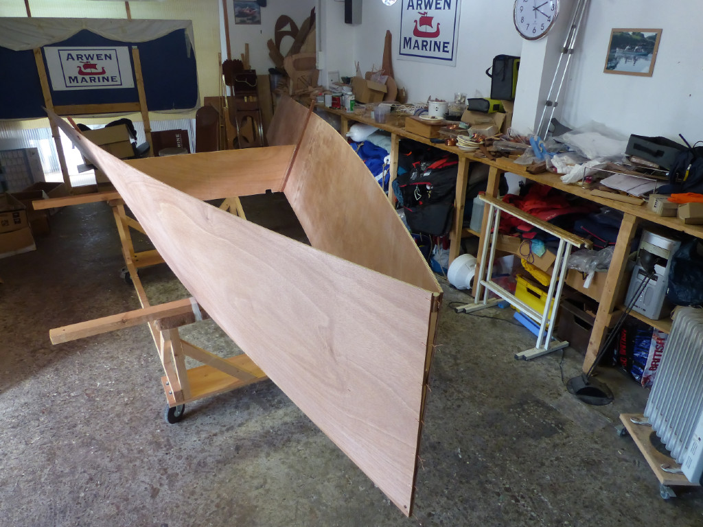 Puis nous fermons l'étrave à l'aide de coutures de fil de cuivre en prenant grand soin d'aligner au mieux les deux extrémités. Une vis traversdante au brion bloque l'alignement. Notez aussi que nous maintenons une ouverture en haut afin d'obtenir un petit arrondi quand elle sera collée à l'époxy. Normalement, une étrave en bois massif fait la liaison entre les deux panneaux, mais nous la remplaçons par un gros joint d'époxy chargée. 