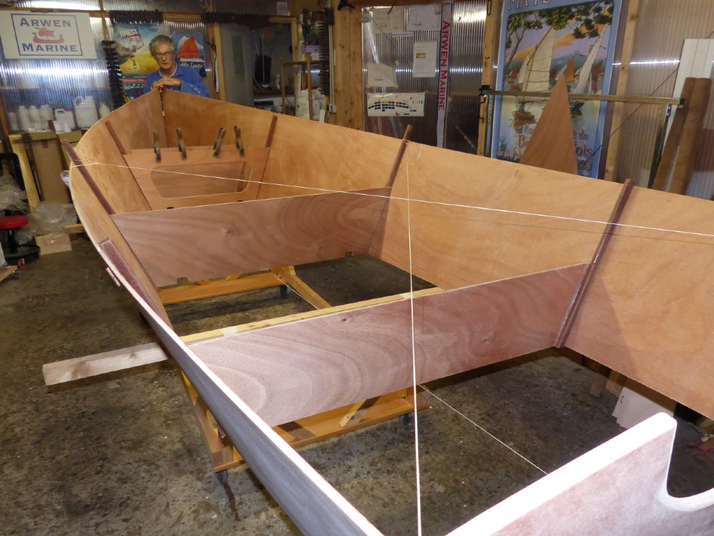 Nous avons ajouté la cloison 1 et réglons l'alignement et la symétrie de ce bébut de coque à l'aide de cordeaux : un pour l'axe et deux pour la symétrie : nous mesurons afin de nous assurer que les transversales sont de longueur égale, tandis que tous les centres des cloisons et du tableau sont alignés.