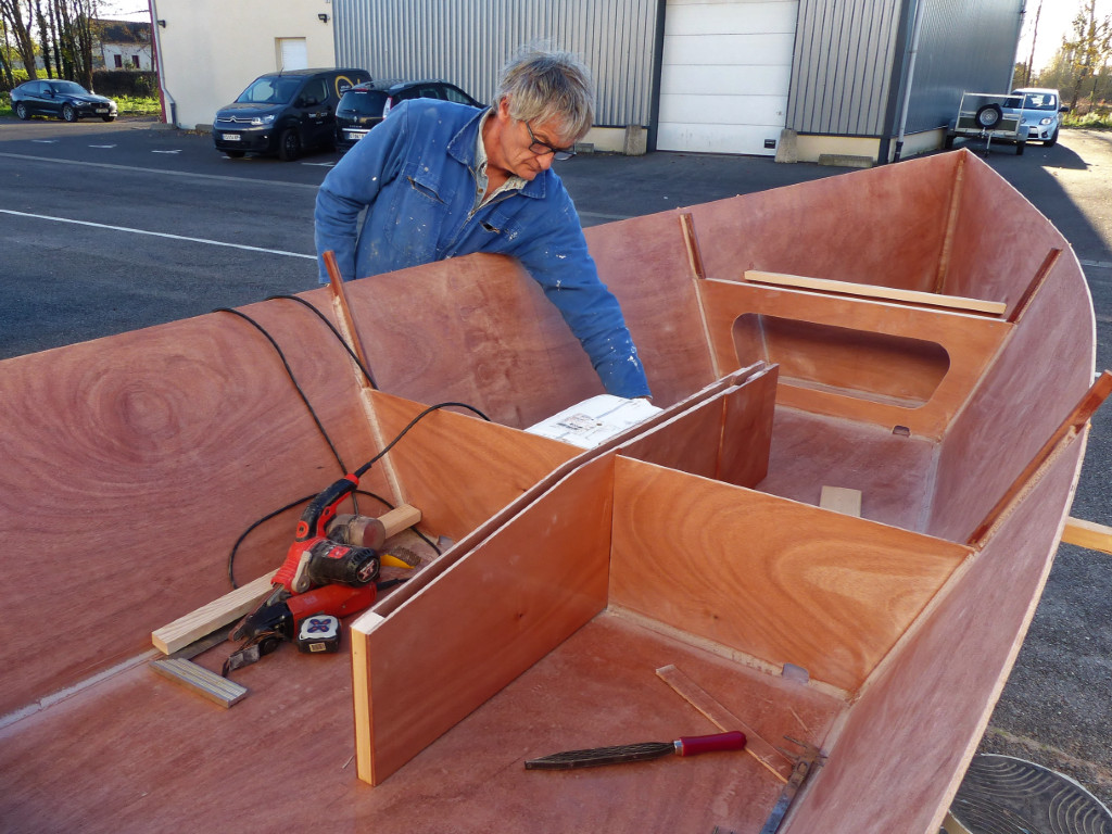 Nous avons coupé le passage du puits de dérive à travers la cloison 3 et ajustons son bord inférieur pour épouser au mieux le cintrage de la sole. Pierre en profite pour valider l'emplacement des 4 bidons de 20 litres de ballast liquide qu'il veut pouvoir embarquer par bonne brise. 