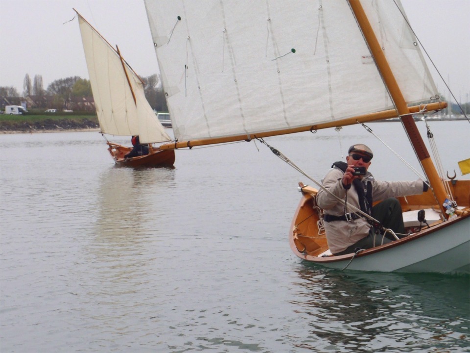 Gérard filme, assis sous le vent pour faire giter "La Marie Pupuce" afin de réduire la surface mouillée. Cette technique est surtout intéressante sur les bateaux plats et larges, et je pense qu'on ne gagne pas grand-chose à faire giter un la carène fine d'un Skerry. C'est "Prise de Ris'k" derrière Gérard. Voir les vidéos de Gérard. 