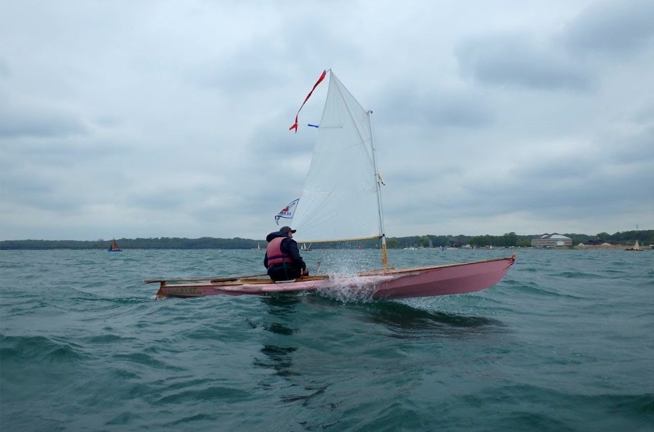 Jolie image de "L'Explorameur" lancé à pleine vitesse. "L'Explorameur" a été construit par Didier à partir d'un kit d'Expedition Wherry qu'il a extensivement modifié afin d'en faire un bateau d'aviron qui marche aussi bien à la voile qu'à l'aviron (l'Expedition Wherry standard marche exclusivement à l'aviron). 