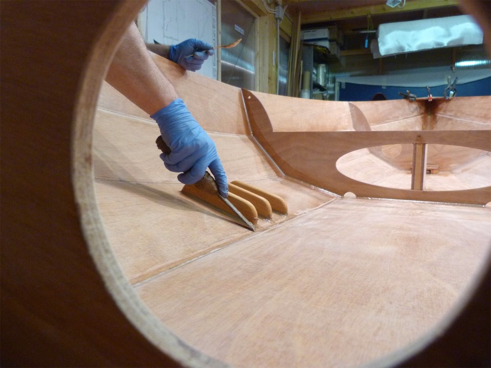 Prise de vue audacieuse &agrave; travers l'ouverture de la trappe du caisson arri&egrave;re. Herv&eacute; est occup&eacute; &agrave; nettoyer les exc&eacute;dents d'&eacute;poxy charg&eacute;e que nous avons utilis&eacute;e pour r&eacute;aliser les petits joints-cong&eacute;s de renfort autour des cale-pieds. 