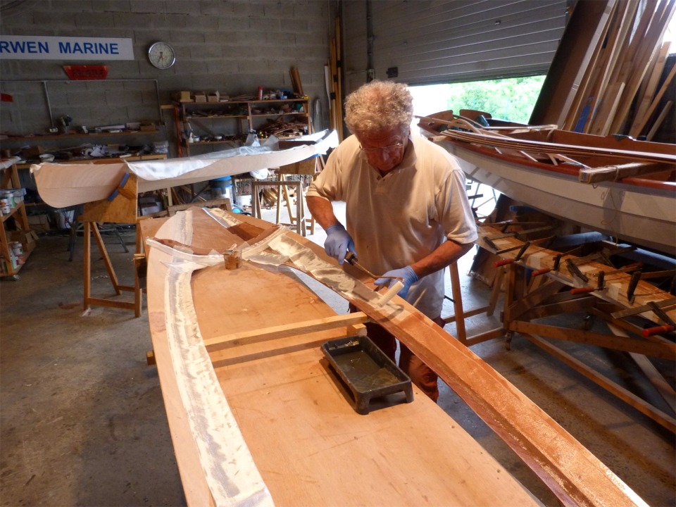 Pierre utilise un rouleau et un pinceau pour saturer la bande de fibre de verre. La fibre de verre devient transparente quand elle est satur&eacute;e d'&eacute;poxy. 