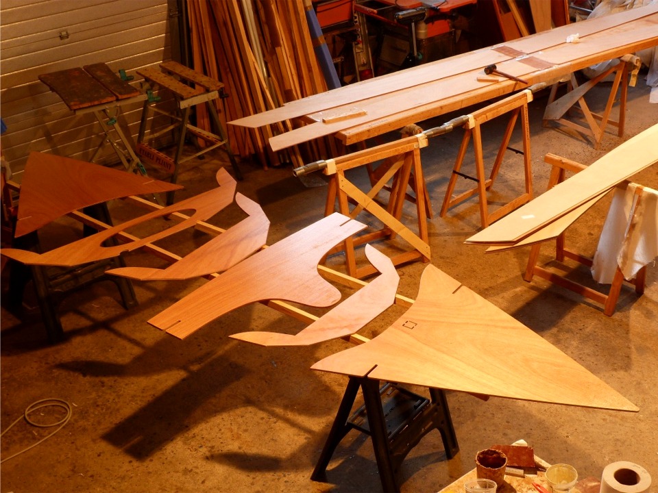 Je viens de passer une couche d'impr&eacute;gnation &eacute;poxy sur toutes les pi&egrave;ces du kit du Skerry autres que les bord&eacute;s et la sole, dont je n'ai pas termin&eacute; de coller les joints-puzzle. On aper&ccedil;oit d'ailleurs les deux bord&eacute;s 3 sur la table de collage &agrave; l'arri&egrave;re-plan &agrave; droite. J'ai utilis&eacute; le maillet pour tapoter les "doigts" afin de les mettre de niveau. On voit que j'ai stratifi&eacute; une bande de fibre de verre d'une douzaine de cm de large par dessus les joints afin de les renforcer. Cette photo aide &agrave; comprendre la l&eacute;g&egrave;ret&eacute; de la coque du Skerry : le nombre d'&eacute;l&eacute;ments de structure et leur taille (et donc leur poids) sont limit&eacute;s au minimum n&eacute;cessaire. Simple et &eacute;l&eacute;gant... 