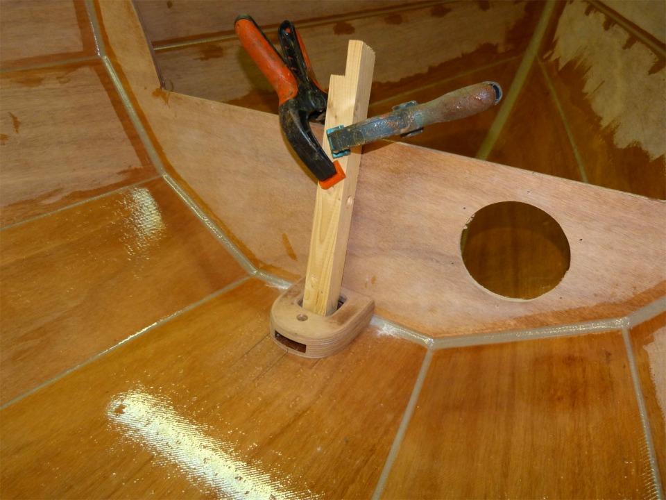 Cette chute de tasseau tenue par les deux pinces me sert &agrave; immobiliser le pied de m&acirc;t &agrave; sa place au pied de la cloison avant. J'ai perc&eacute; les trous de ses 4 vis de fixation par l'int&eacute;rieur, les ai frais&eacute;s par l'ext&eacute;rieur (pour les t&ecirc;tes des vis), puis ai marqu&eacute; le pied de m&acirc;t en per&ccedil;ant l&eacute;g&egrave;rement &agrave; travers les trous. Plus qu'&agrave; d&eacute;monter le tasseau, retourner le pied de m&acirc;t et faire de vrais avant-trous de la bonne profondeur. 