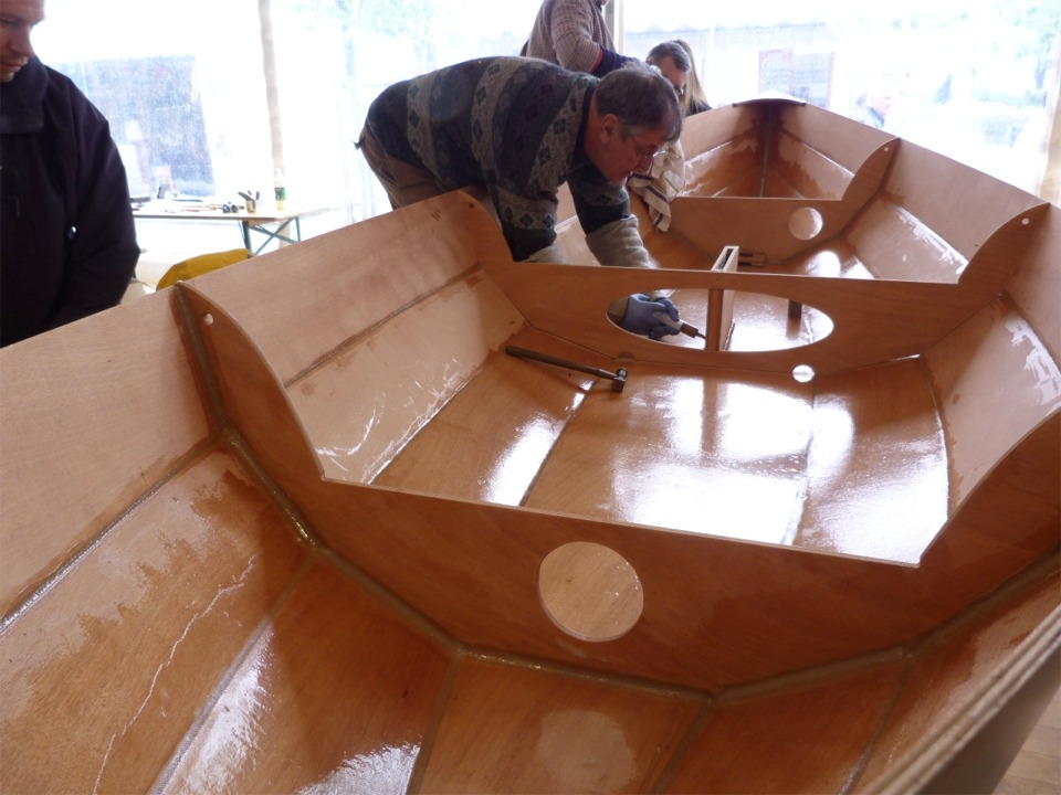 Après un premier montage à blanc (vissé sans époxy) du puits de dérive et du pied de mât, nous avons tout démonté, encollé les chants, et remonté. Chrsitian est ici occupé à déposer un gros filet d'époxy "crème de marrons" dans l'angle du pied du puits de dérive, afin d'y faire un gros joint-congé. 