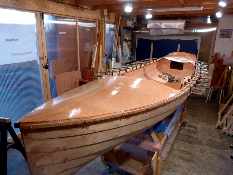 Nous avons dû utiliser des vis, dont on voit les bouchons sur bâbord avant, pour presser le collage des listons le long des pontages avant et arrière, car on ne peut bien sûr pas mettre de presses à ces endoits. Le perçage des vis affaiblit la latte de sapelli et nous avons bien cru, tant sur tribord que sur bâbord, qu'elle allait casser au moment du cintrage du premier mètre à l'avant, qui est sévère.