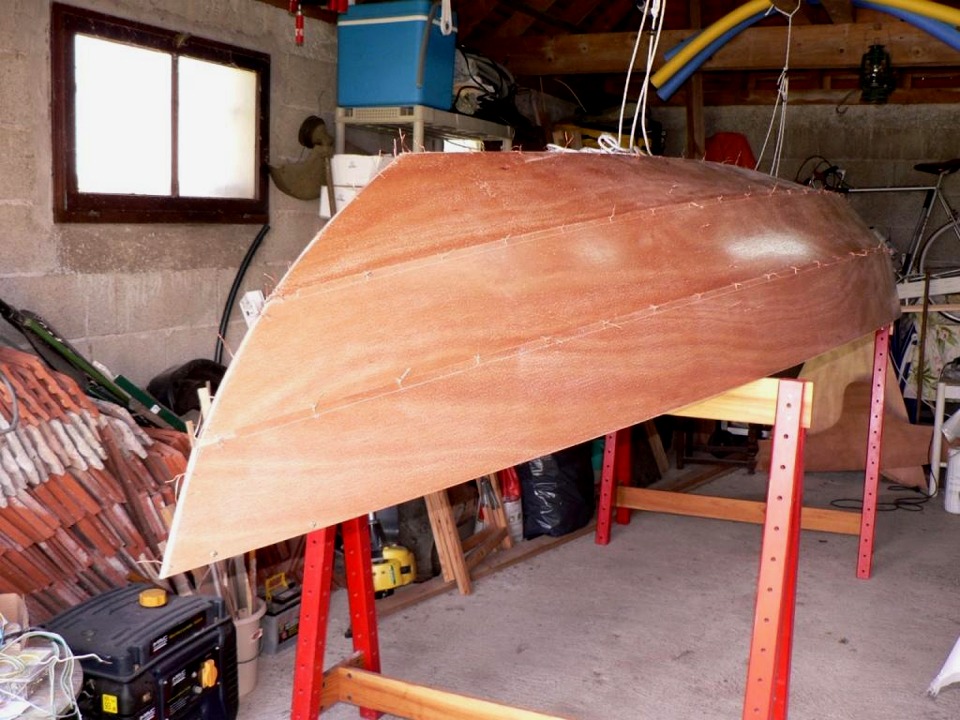 Richard a retourn&eacute; sa coque afin de commencer le collage. Notez qu'il a pris le temps et la peine d'impr&eacute;gner toutes les pi&egrave;ces d'&eacute;poxy claire afin de durcir et prot&eacute;ger la surface du contreplaqu&eacute; okoum&eacute;. 