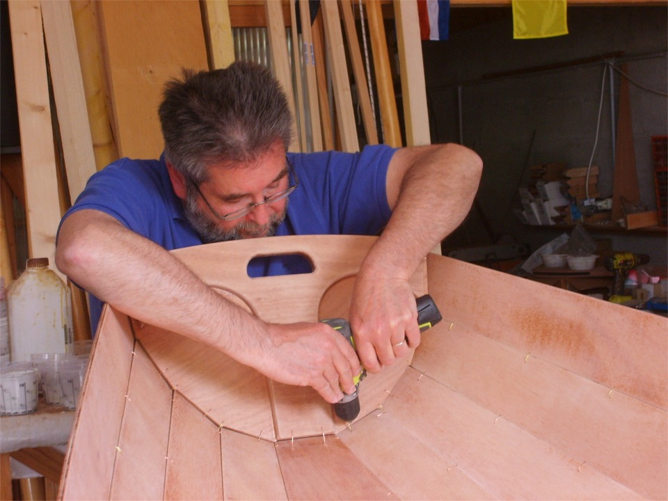 Sur cette photo de Dominique, je perce de nouveaux trous pour les sutures de la marotte, d&eacute;ja en place, car les trous pr&eacute;-perc&eacute;s du kit sont un peu trop proches de l'extr&eacute;mit&eacute; des panneaux (sole et bord&eacute;s 1) et il est un peu d&eacute;licat de suturer la marotte de sorte &agrave; ce qu'elle s'inscrive &agrave; l'int&eacute;rieur des extr&eacute;mit&eacute;s des panneaux, sur tout son pourtour. 