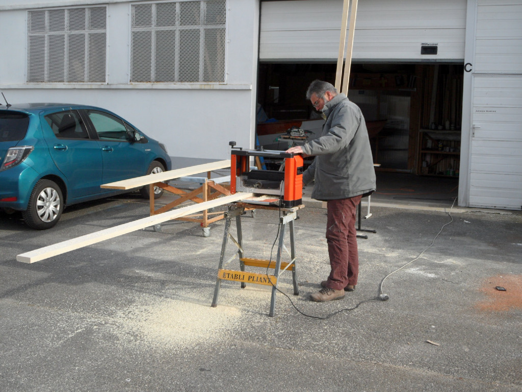 Comme résumé ci-dessus, nous avons commencé par quelques journées de préparation avant de démarrer la construction du bateau lui-même. Ici, je passe dans le rabot les trois lattes que nous allons coller pour faire le mât, et les quatre de la bôme et de la vergue (deux pour chacune). 