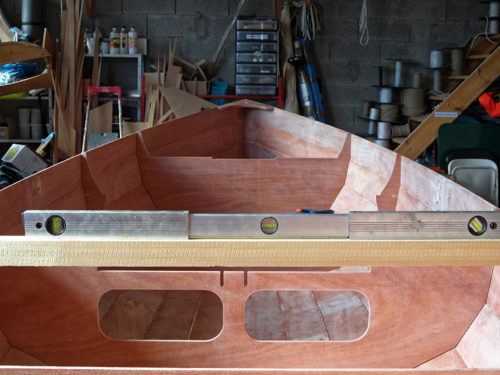 Cette dernière vis clôture le montage de la coque. Nous resserrons toutes les sutures sur lesquelles nous étions passés trop vite, puis nous promenons ce tasseau avec le niveau à bulle d'avant en arrière sur le haut des carreaux afin de vérifier que la coque n'est pas vrillée. 