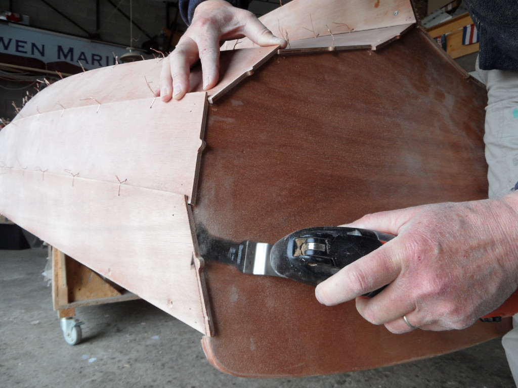 Puis nous coupons l'extrémité des virures au ras du tableau à l'aide d'une scie oscillante. Notez que nous avons positionné le tableau en laissant dépasser les virures tout autour sur une longueur de quzlques millimètres (0 à 10 mm). 