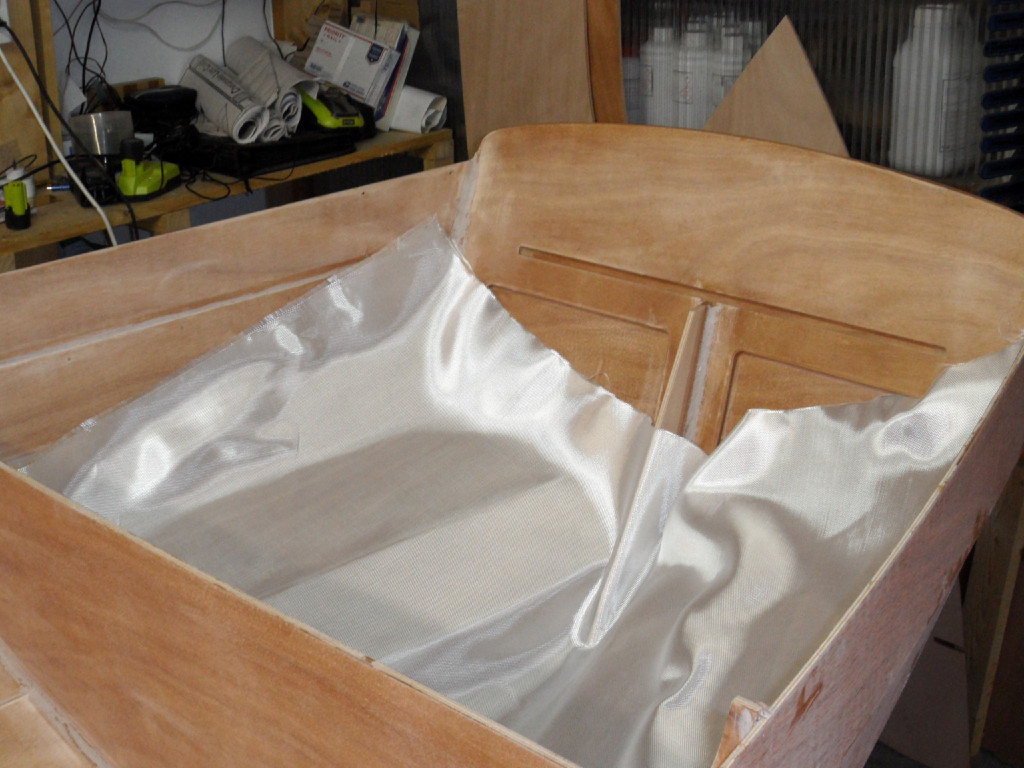 Nous rentrons pour faire la stratification de la surface intérieure. Nous découpons une pièce de tissu pour le coqueron arrière et une pour le coquerons avant. il peut être plus facile de croiser deux pièces qui seront plus faciles à draper sur la surface. Dans ce cas on laisse au mimimum une dizaine de cm de recouvrement au fond du compartiment. 