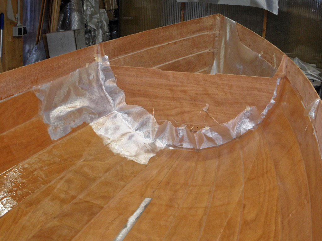 On laisse dépasser le tissu sur les cloisons, et on veille à le saturer jusqu'à couvrir le joint-congé qui colle la cloisons sur le bordage. On coupera plus tard l'excédent de tissu sur le joint-congé à l'aide de la pointe d'un cutter. Cette opération est effectuée dès que l'on a terminé de satruer le tissu. 