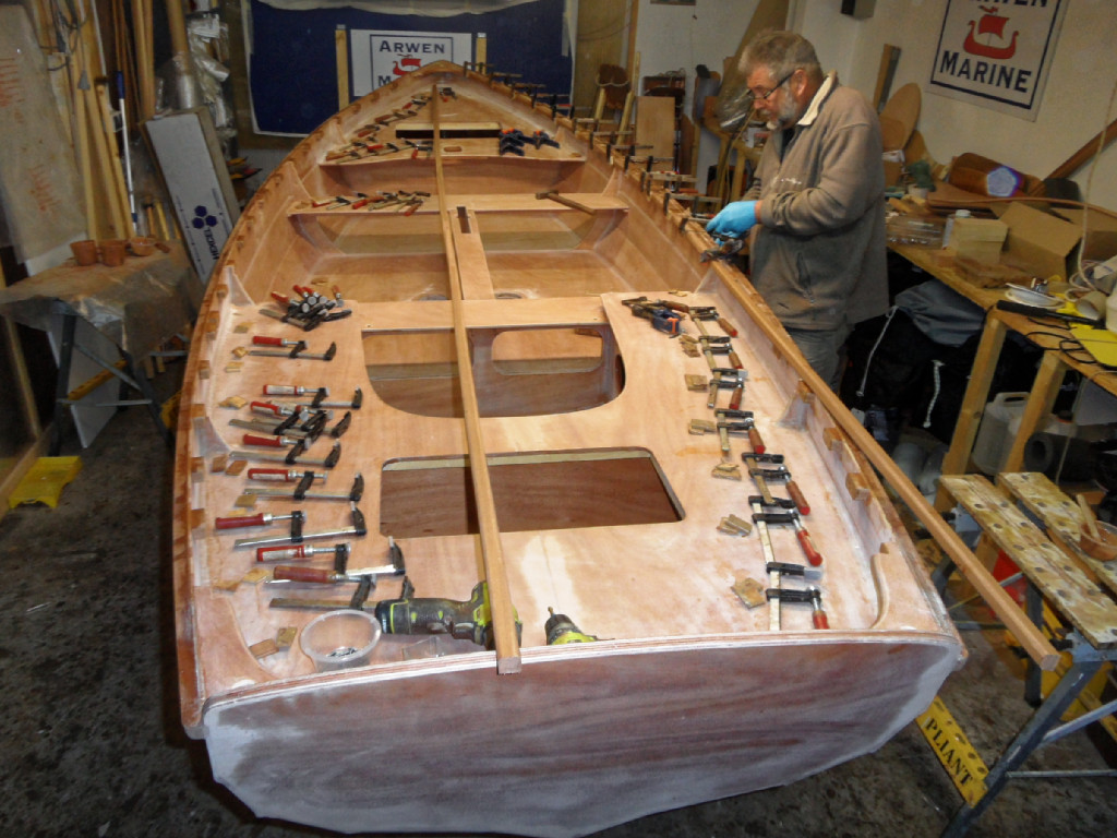 Je suis en train de coller la serre tribord. On voit que nous avons arrondi les deux arêtes de la face de la serre qui sera vers l'intérieur du bateau. Je couperai l'excédent de longueur de la serre juste avant de mettre en place les serres des deux dernières cales et de la courbe arrière, bien entendu. Notez que nous mettons deux martyrs sous les presses : un sur la serre, et un sur le liston. 